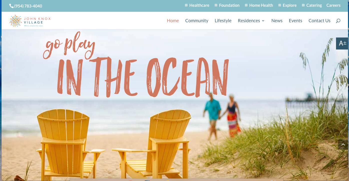 Two empty chairs facing the ocean with people walking along the beach in the background.